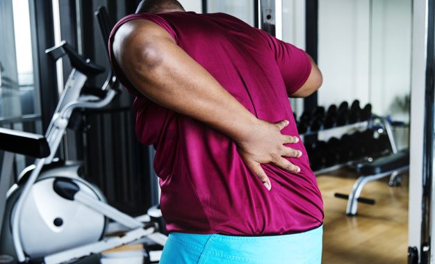 A man holding his waist in a gym
